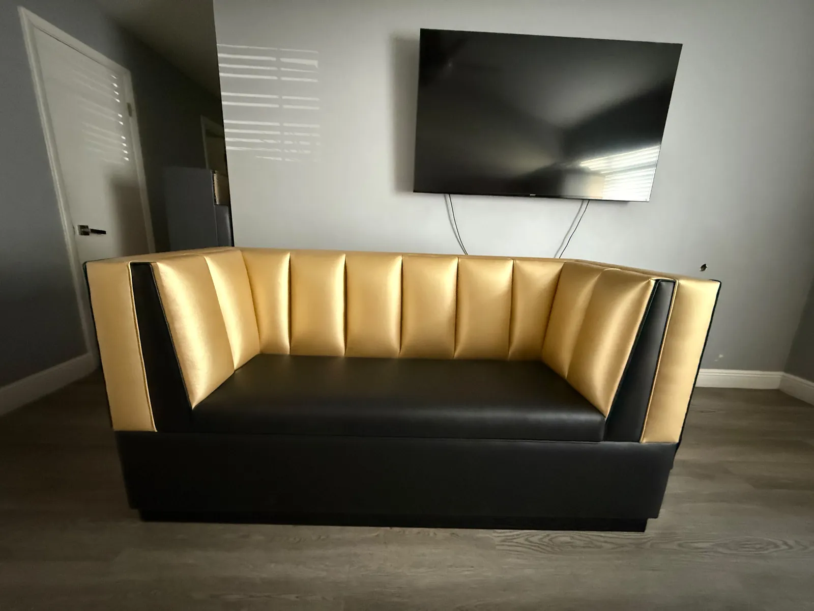 Two-tone booth sofa with a gold channel back and black vinyl seat and base