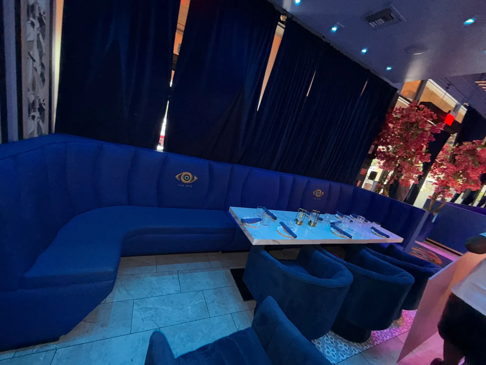Navy velvet curved booth with an embroidered crest on the back, set around a dining table in a lounge