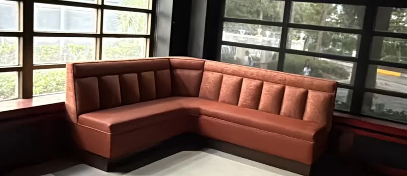 Terracotta channel-back L-shaped booth installed along a window wall