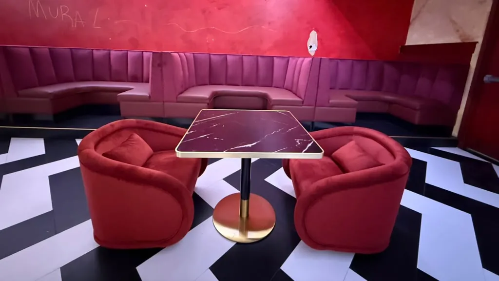 Row of magenta channel-back booths along a red wall in a restaurant with black and white floor