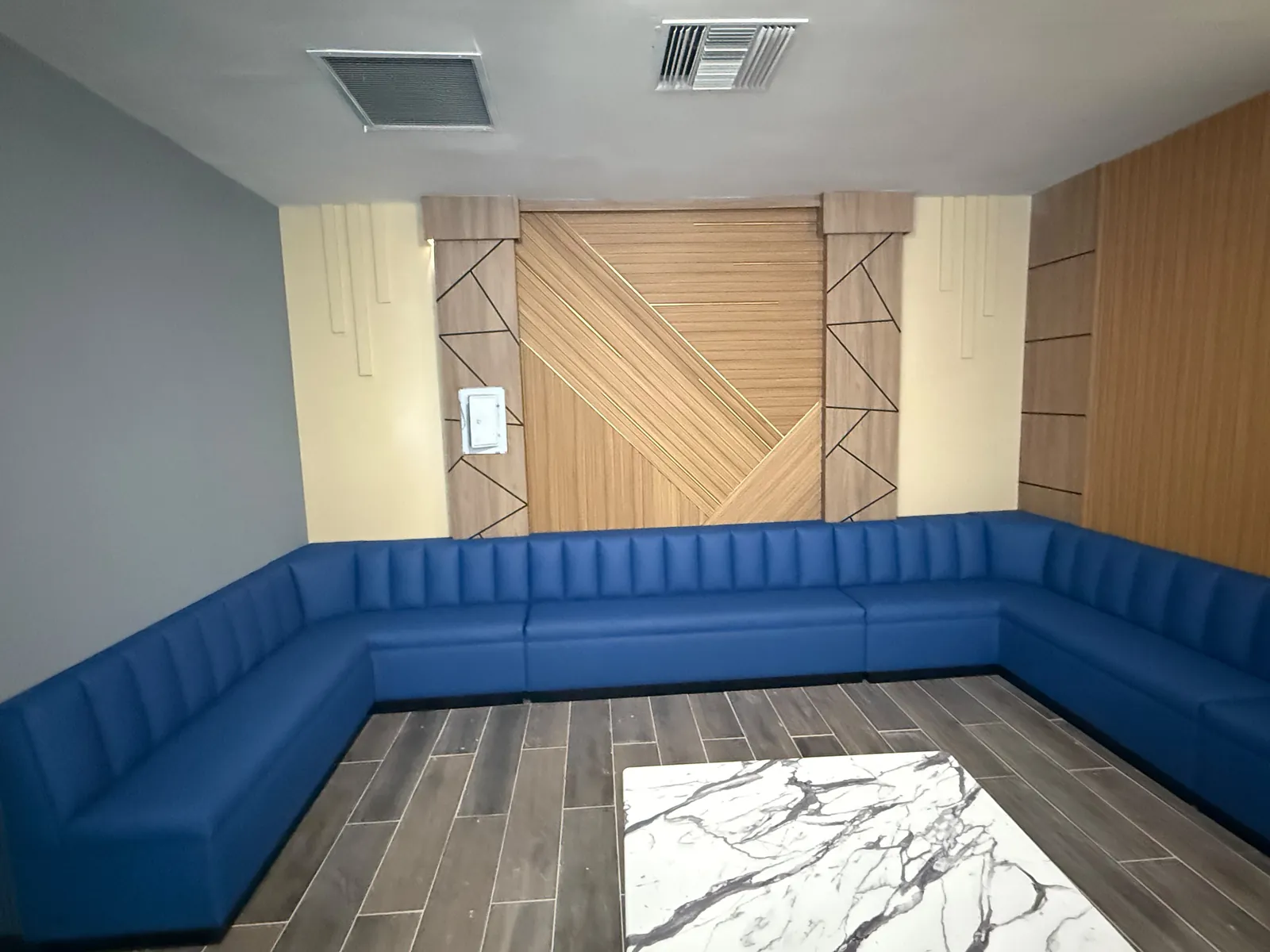 U-shaped navy channel-back booth seating running along three walls of a private room